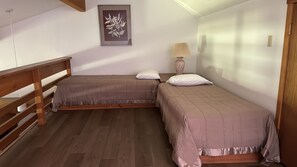 A bedroom with two single beds, a wooden headboard, a bedside lamp, and a framed artwork on the wall. - Desirable 1-bedroom & Loft condo in Wilson perfect for your getaway (Wilson)
