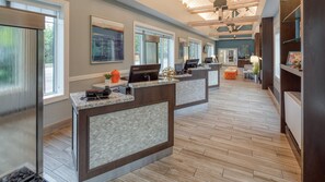 A hotel reception area with marble counters, large windows, and a wooden floor.