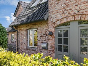 A brick house with a grey door, a window, and a solar panel on the roof. - Holiday Home in Sylt With 3 Bedrooms (Sylt)