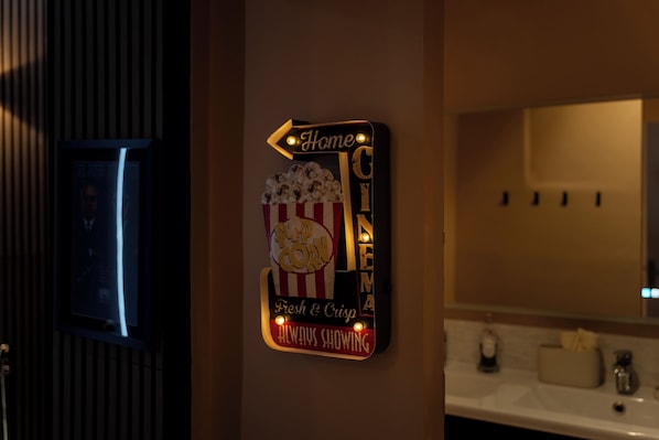 Segnaletica a parete con tema cinema e popcorn, che indica un'area dedicata alla visione di film.