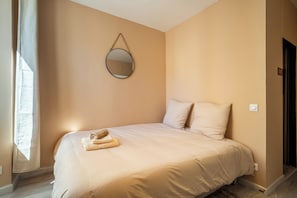 Una camera da letto con un letto, cuscini, uno specchio e una finestra.
