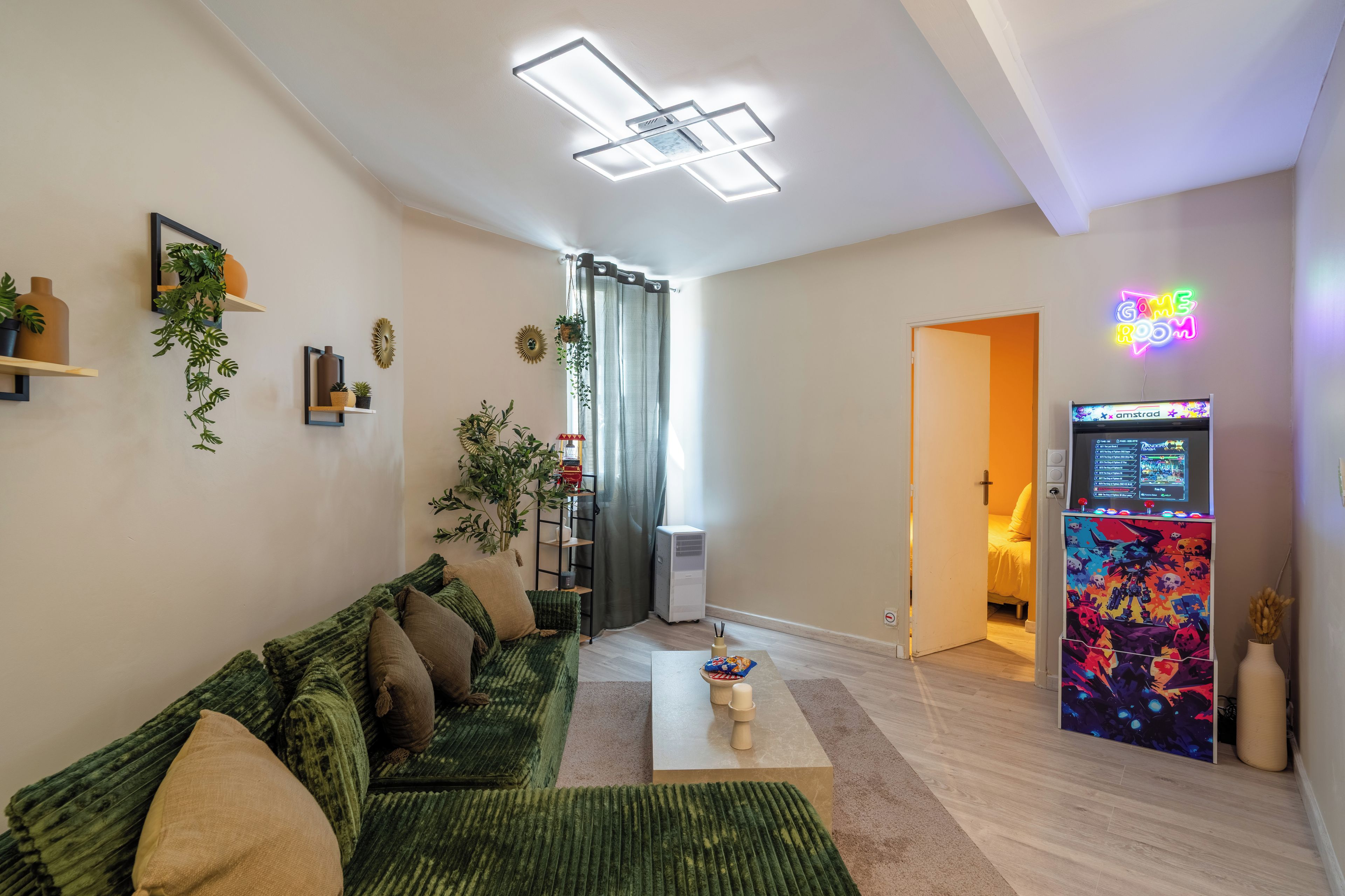A modern living room with a green sofa, a flat-screen TV, and a neon sign.