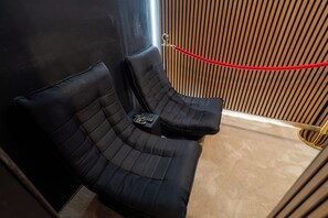 Eine schwarze Ledersofa mit einer Fernbedienung darauf, neben einer Wand aus vertikalen Holzleisten platziert.