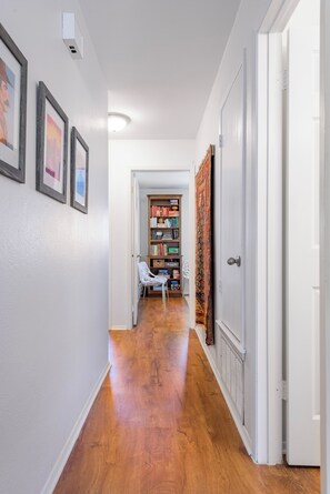Ein Flur mit Holzboden, weißen Wänden und einem Bücherregal mit Büchern und Dekorationsobjekten.