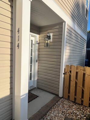 A house entrance with a mailbox, a wooden fence, and a mailbox number 414. - The 414: Beach Retreat, Arcade, Fireplace, & Garage (Virginia Beach)