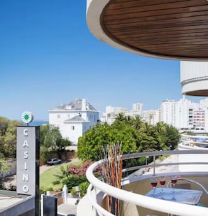 Un balcó amb vista a un edifici de casino, un edifici blanc amb cúpula, i un paisatge urbà al fons.