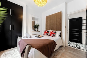 Quarto moderno com cama grande, guarda-roupa, espelho e lustre.