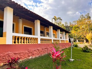 A building with a yellow facade, white columns, and a red base. - Pousada Sierra (Serra Negra)