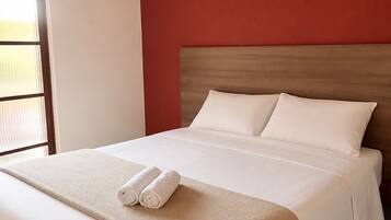 Une chambre d’hôtel avec un lit, deux tableaux accrochés au mur et une fenêtre avec des stores.