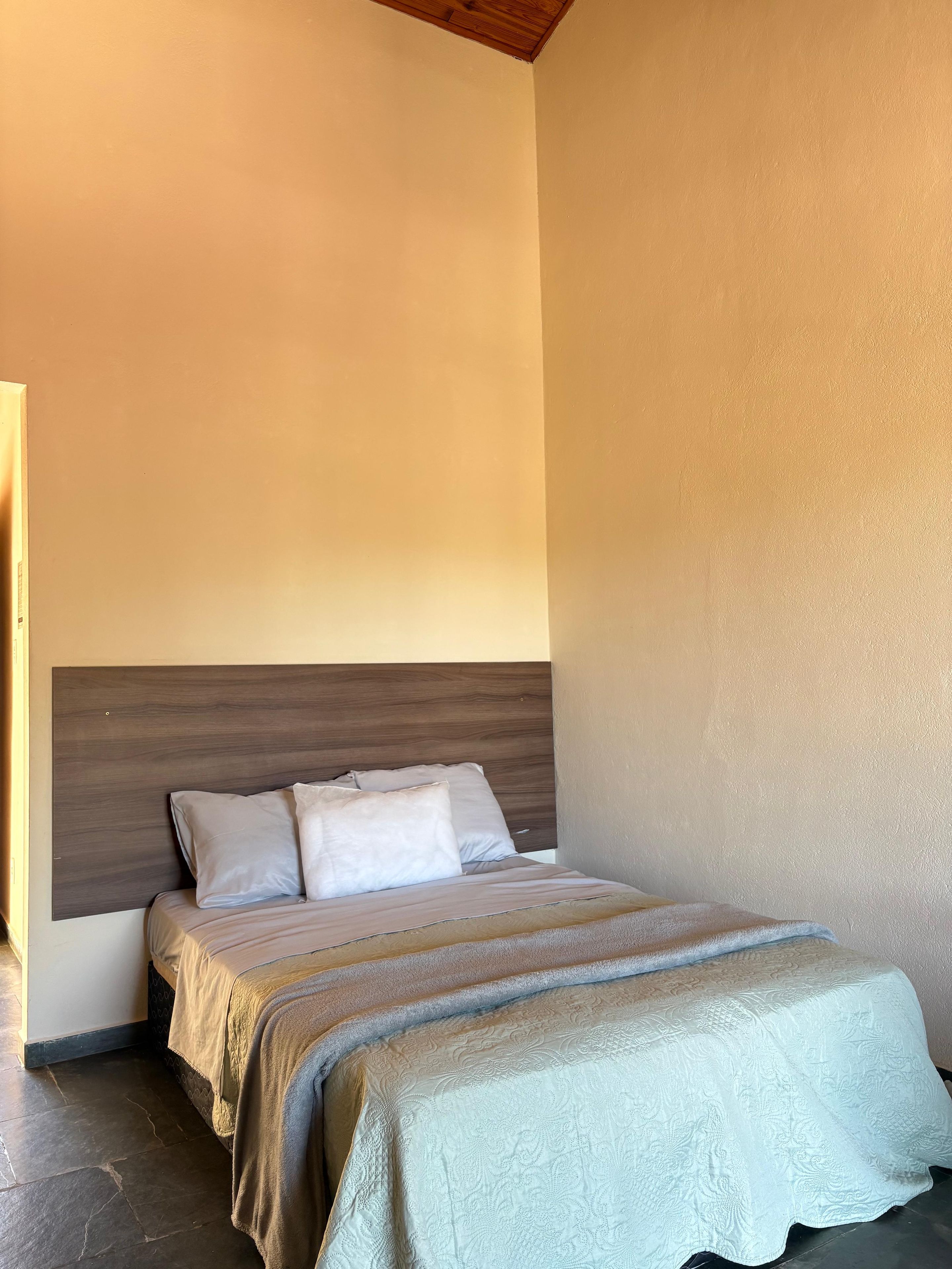 Quarto com cama, cabeceira e colcha estampada.
