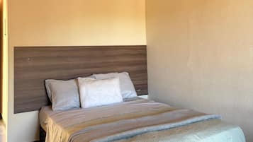 Quarto com cama, cabeceira e colcha estampada.