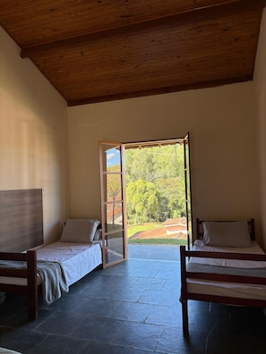 Une chambre avec deux lits, un plafond en bois et une vue sur la verdure.