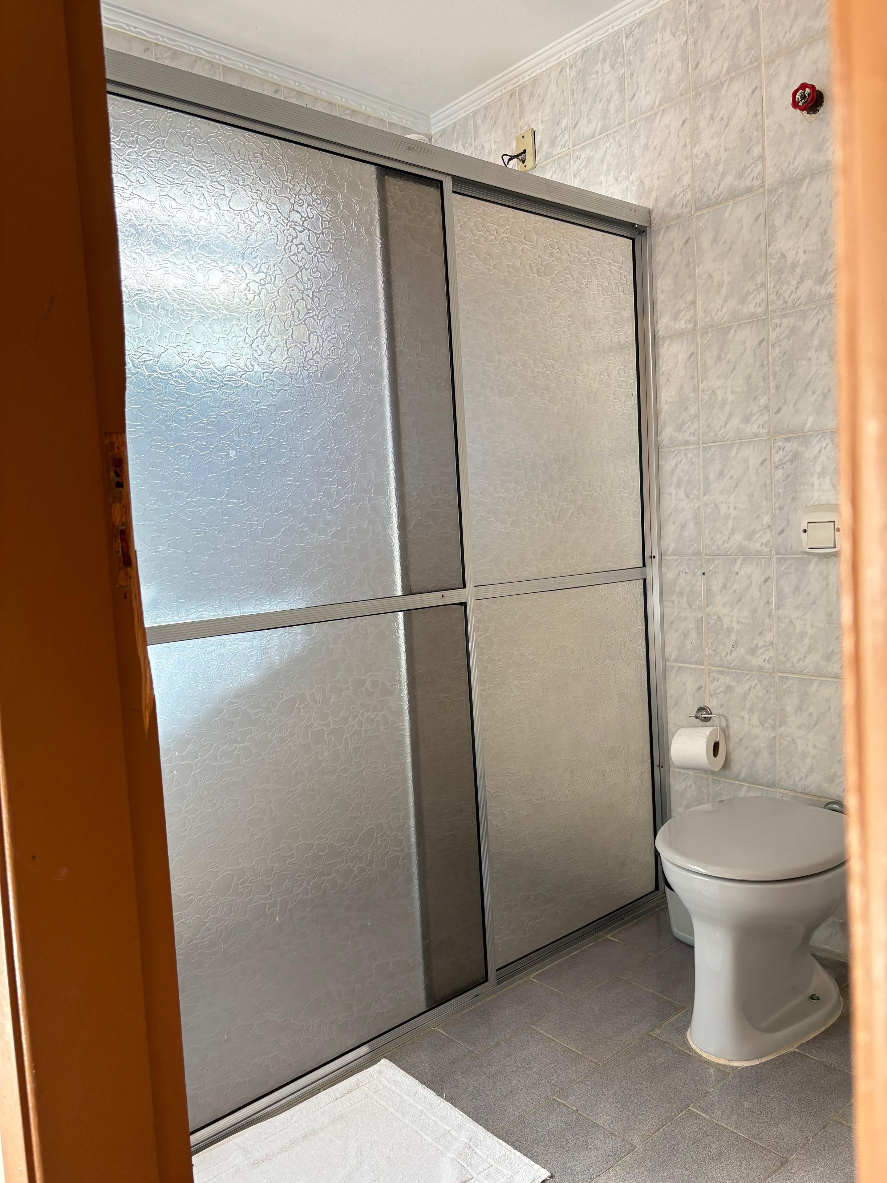 Ein Badezimmer mit Toilette, Handtuch und Duschkabine.
