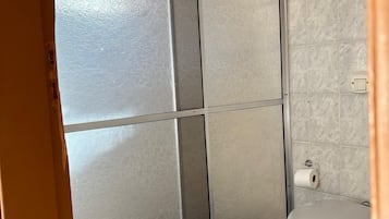 A bathroom with a toilet, a towel, and a shower enclosure.