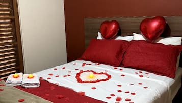 A bed with red and white bedding, heart-shaped pillows, and a heart-shaped decoration on the bedspread.