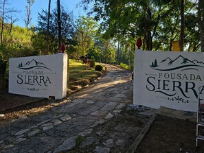 Un camino de piedra que conduce a un letrero con la inscripción 'Pousada Sierra'.