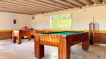 Une table de billard dans une pièce dont le sol est carrelé et qui possède une fenêtre.