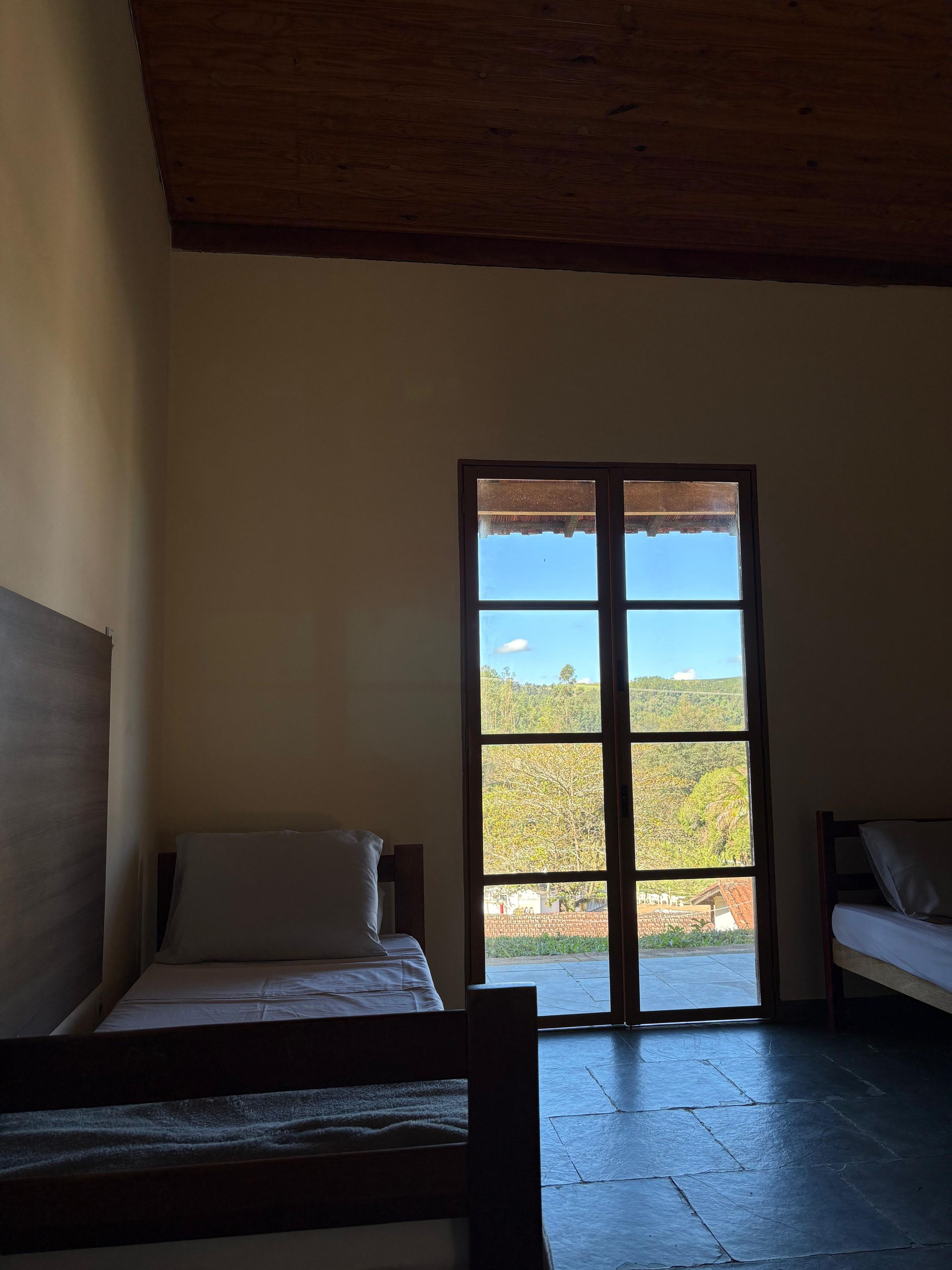 Una habitación con una cama, un banco y un ventanal con vistas al paisaje.