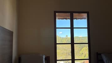 Una habitación con una cama, un banco y un ventanal con vistas al paisaje.