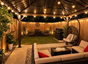 An outdoor patio with a fire pit, seating area, and a hanging chair.