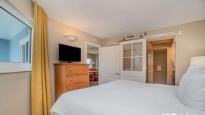 Ein Hotelzimmer mit Bett, Fernseher auf einem Holzkoffer, Kleiderschrank und Badezimmer mit Dusche und Toilette.