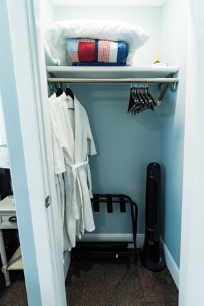 A small bathroom with a towel rack, a heater, and a shelf with folded towels.