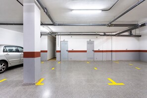 Eine Parkgarage mit mehreren Einfahrten, ausgewiesenen Stellplätzen und einem geparkten Auto auf einem Platz.