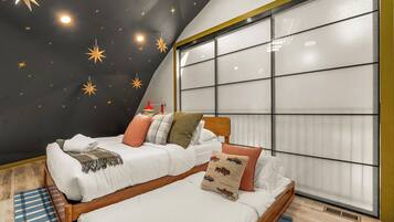 Un dormitorio con techo estrellado, un ventanal grande y una cama con muchas almohadas.