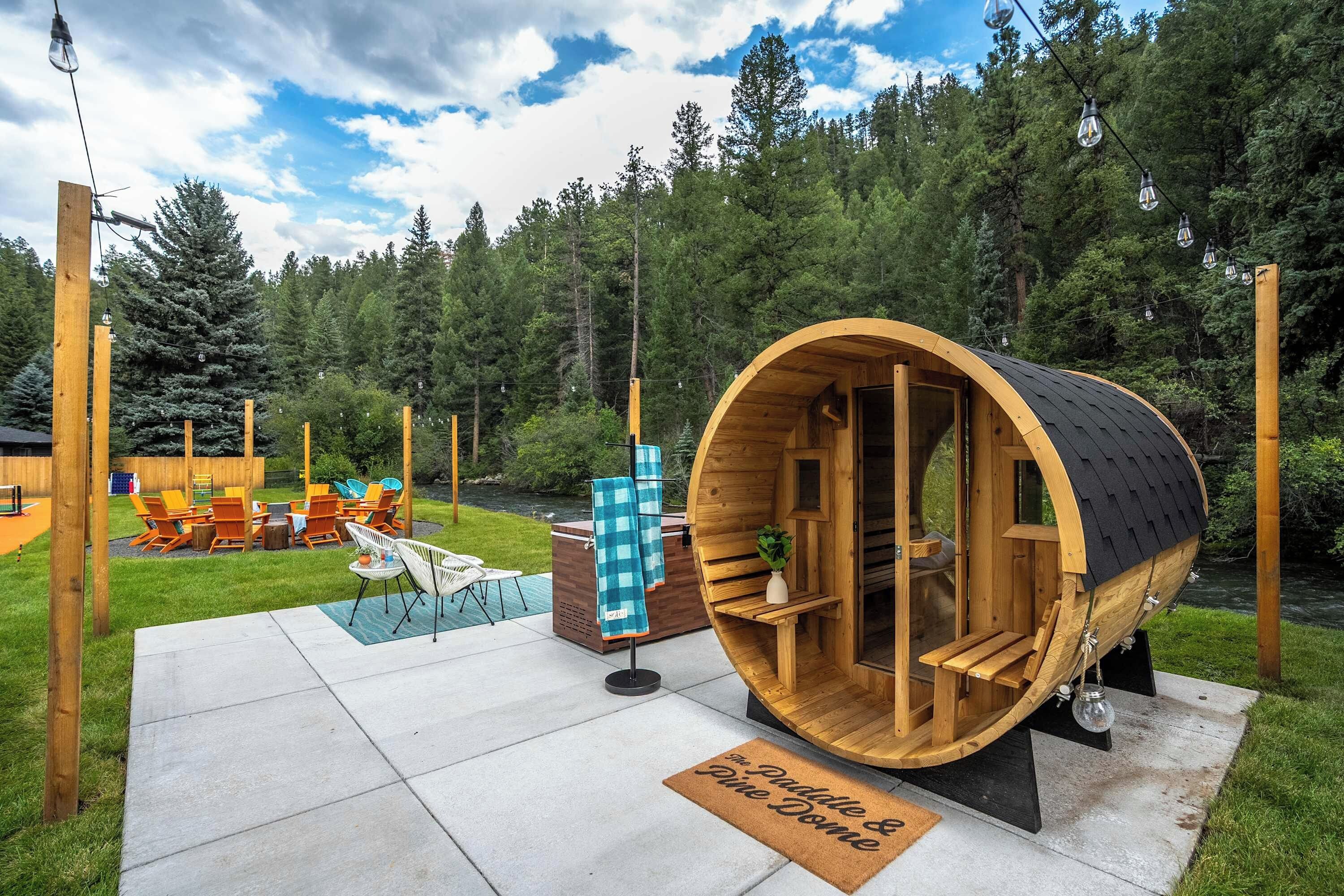 A wooden barrel structure with a bench inside, surrounded by a deck and outdoor seating area.