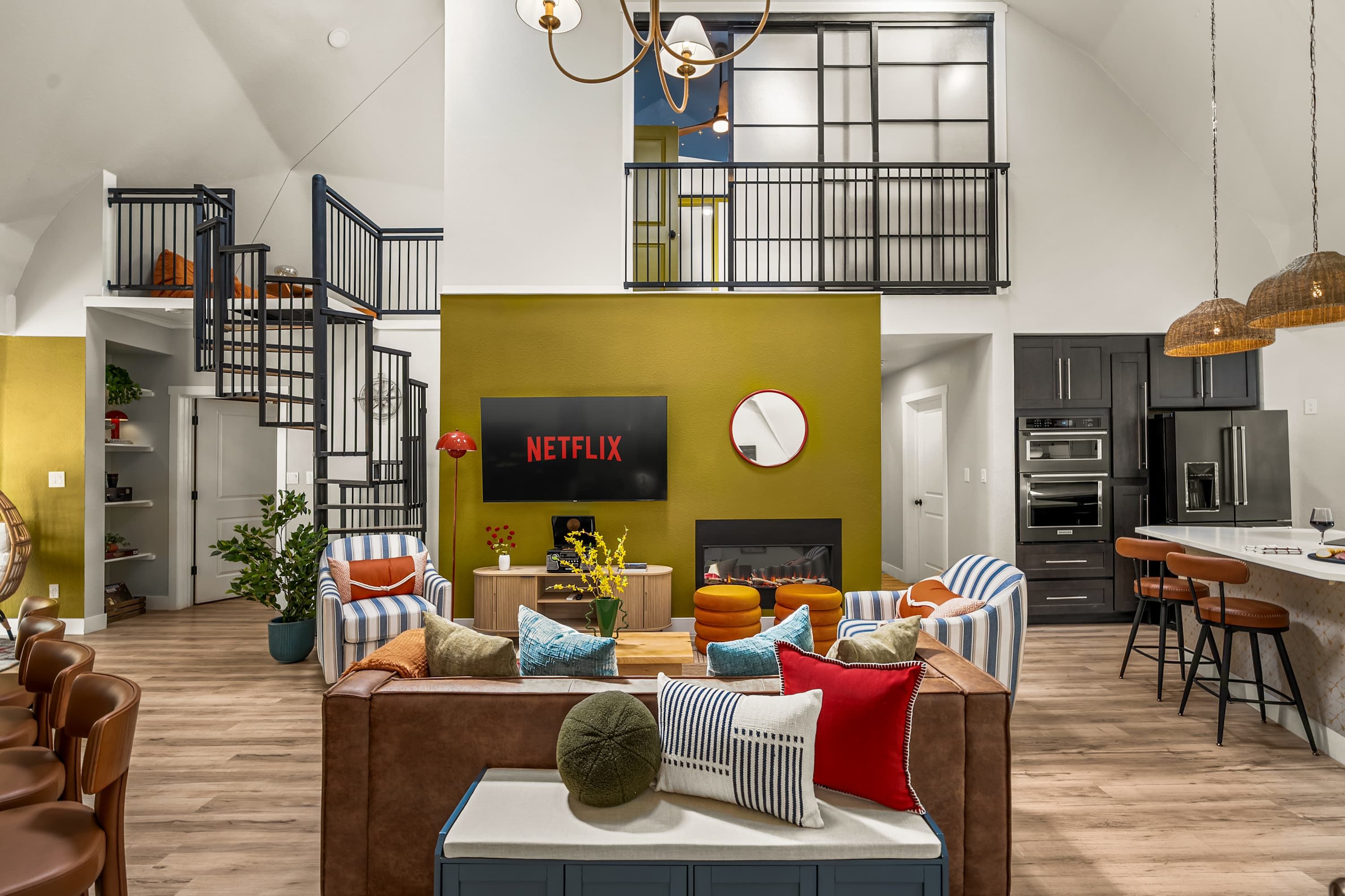A modern living room with a fireplace, a television, and a staircase leading to an upper level.