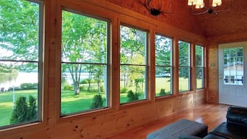 Ein Zimmer mit großen Fenstern, einer Holzbalkendecke und einem schwarzen Ledersofa.