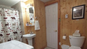 Ein Badezimmer mit Duschvorhang mit Tiermotiv, einem Waschbecken, einer Toilette und einem Spiegel.