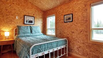 A bedroom with a bed, two windows, and a ceiling light.