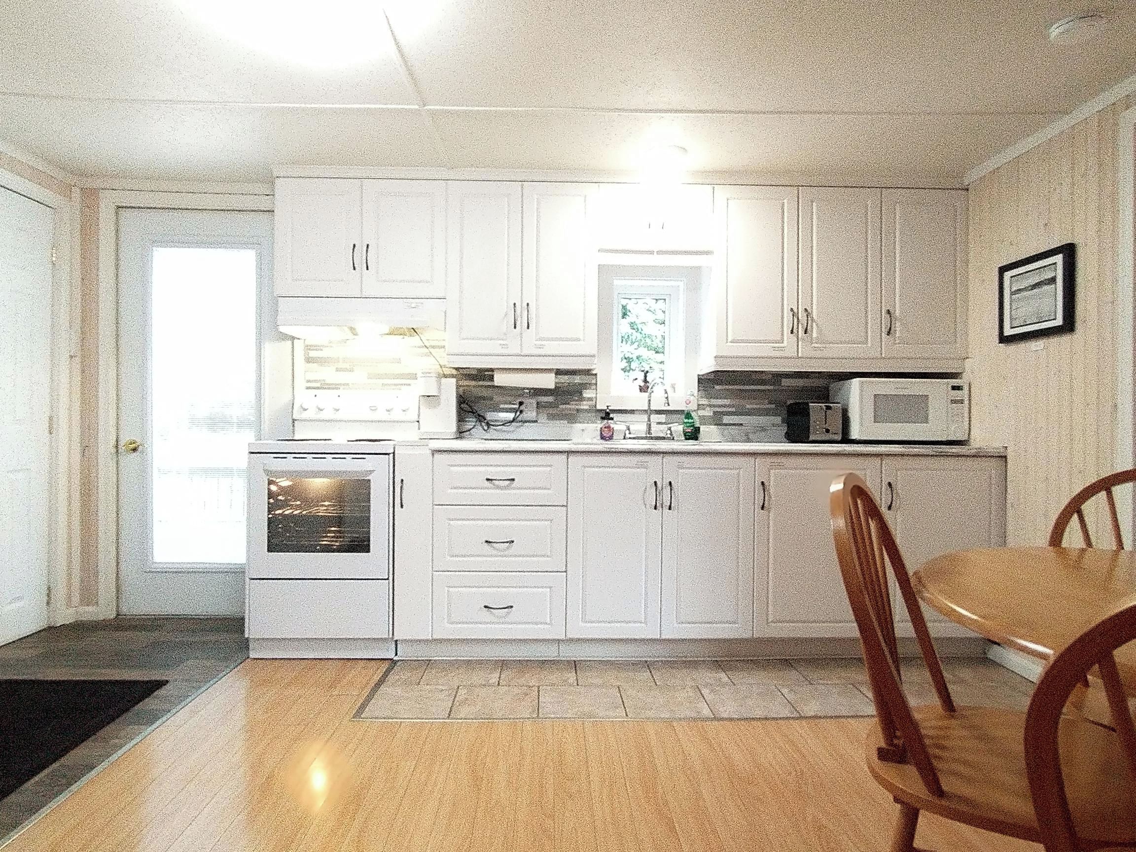 A kitchen with white cabinets, a microwave, and a stove. There is a dining table with chairs.