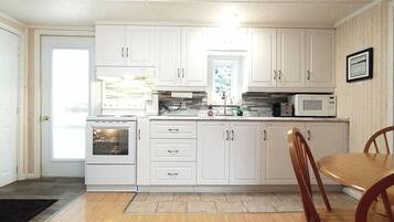 A kitchen with white cabinets, a microwave, and a stove. There is a dining table with chairs.