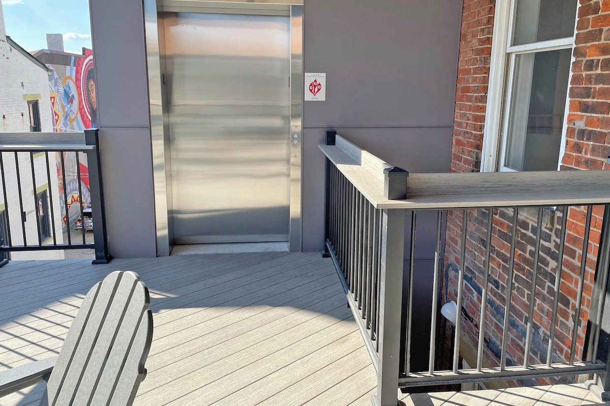 A building entrance with a closed metal door, a wooden deck, and a metal railing.