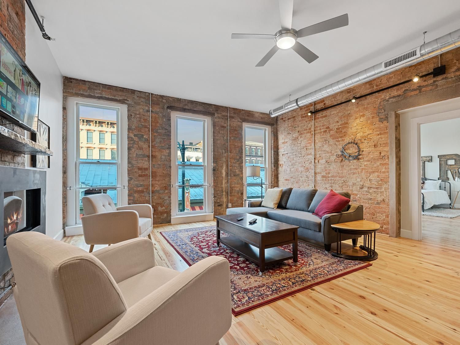 A modern living room with a fireplace, a sofa, a coffee table, and a view through large windows.