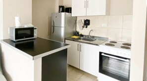 A compact kitchen with a microwave, refrigerator, sink, and oven. - Amanecer del Fuego V (Ushuaia)