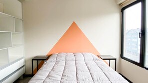A bedroom with a bed, a white wardrobe, a small table, and a window with a view of buildings. - Amanecer del Fuego V (Ushuaia)