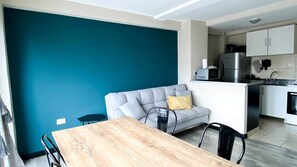 Eine moderne Küche mit weißen Schränken, einem grauen Sofa und einem Holzesstisch.