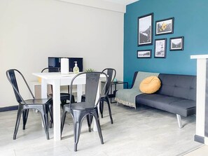 A modern living room with a dining area, a sofa with a cushion, and a wall with framed pictures. - Amanecer del Fuego IV (Ushuaia)