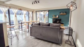 Ein Wohnzimmer mit einer Couch, einem Esstisch und einem Fernseher.