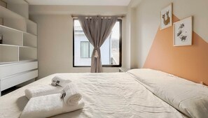 Une chambre d’hôtel avec un lit, une armoire, une fenêtre avec des rideaux et des œuvres d’art accrochées au mur.