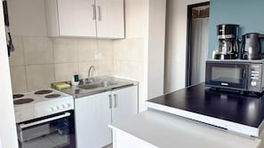 A kitchen with a stove, oven, sink, and microwave. - Amanecer del Fuego VII (Ushuaia)
