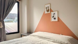 A bedroom with a bed, a nightstand, a window with curtains, and two framed pictures on the wall. - Amanecer del Fuego VII (Ushuaia)