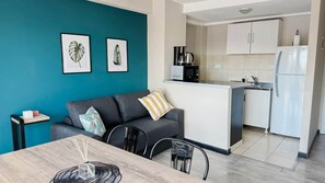 A modern living space with a sofa, a dining table, and a kitchenette area. - Amanecer del Fuego VI (Ushuaia)