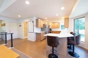 A modern kitchen with a central island, bar stools, and a view of the outdoors. - 4BR Eagle River Chain Lakefront | Walk Downtown (Eagle River)