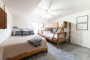 Ein Schlafzimmer mit zwei Etagenbetten, einem Einzelbett und einem Deckenventilator.