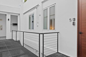 A modern building exterior with a metal railing, a fire exit sign, and a door marked with the number 5. - Casa Valencia | Old San Juan (San Juan)