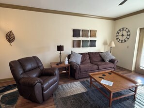 A living room with a leather chair, a brown sofa, a wooden coffee table, and a wall clock. - Updated Pigeon Forge Condo.  3BDR 2BA W/ 2 Pools on the Parkway (Pigeon Forge)